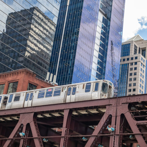 Chicago cityscape, spring day. Chicago train on a steel bridge, downtown on high rise buildings background, low angle view