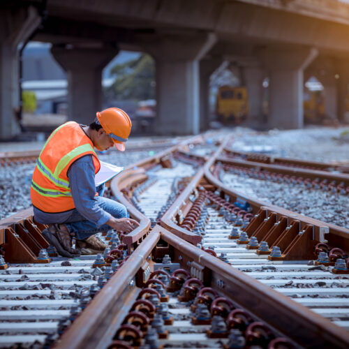 Portrait engineer under inspection and checking construction process railway switch and checking work on railroad station .Engineer wearing safety uniform and safety helmet in work.